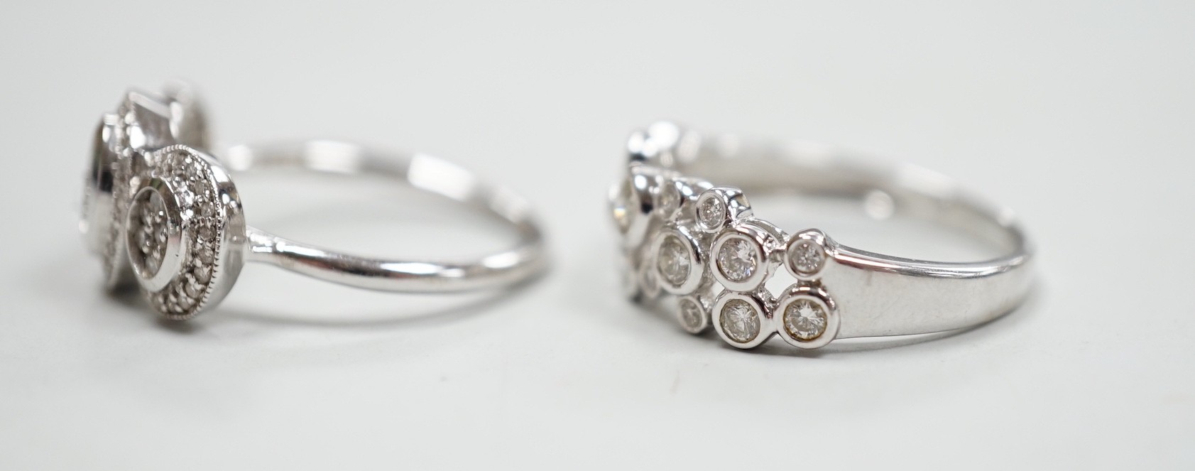 A modern 18ct white gold and diamond set triple cluster ring, size M and a similar 18ct white gold and collet set diamond cluster ring, size N, gross weight 7.5 grams.